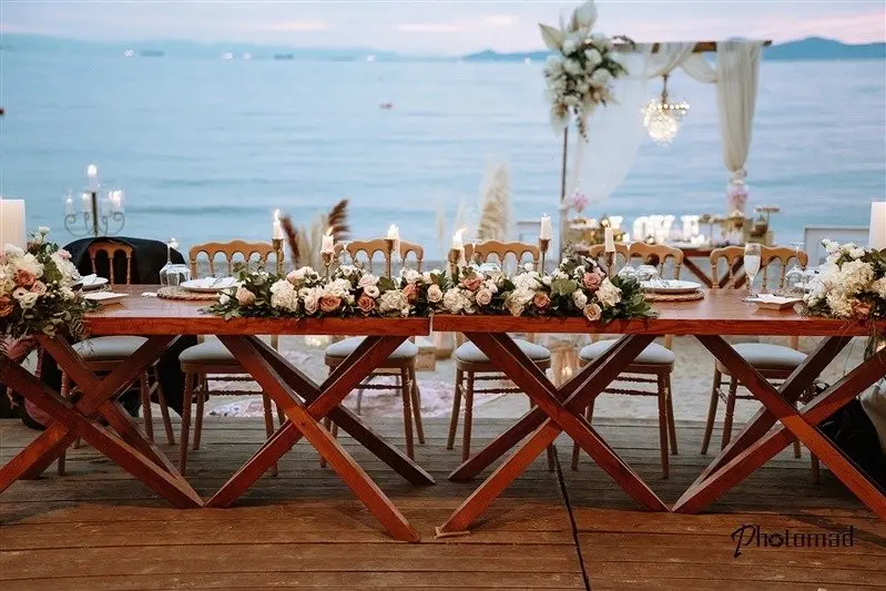 Νυφικό τραπέζι με λουλούδια και λευκό styling πάνω από τη θάλασσα