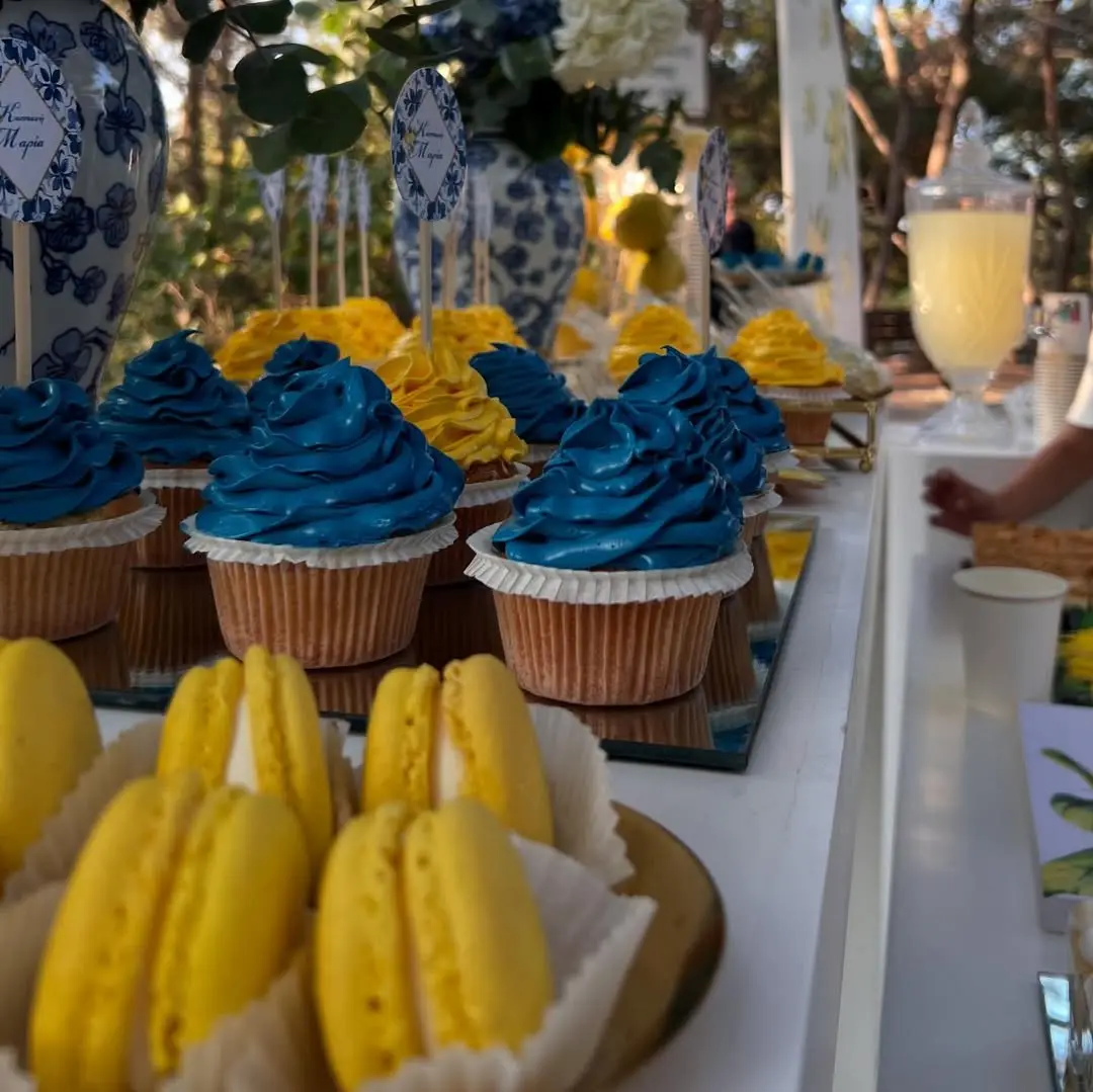 Μπλε cupcakes και κίτρινα macarons σε candy bar βάπτισης